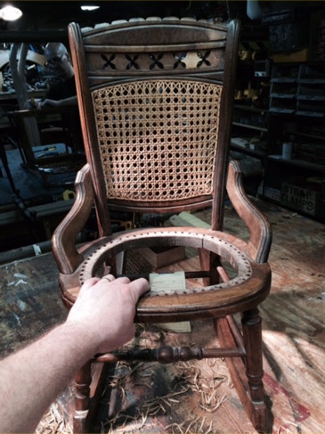 Wooden chair with a newly caned seat; the carved back splat shows where a missing piece of detail was restored.