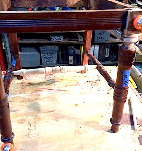 Side chair rebuilt on the workbench after heavy damage, with a newly turned stretcher fitted between the legs.